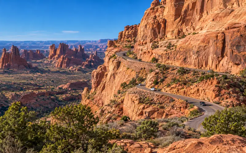 The Arches entrance road switchbacking up a red sandstone cliff