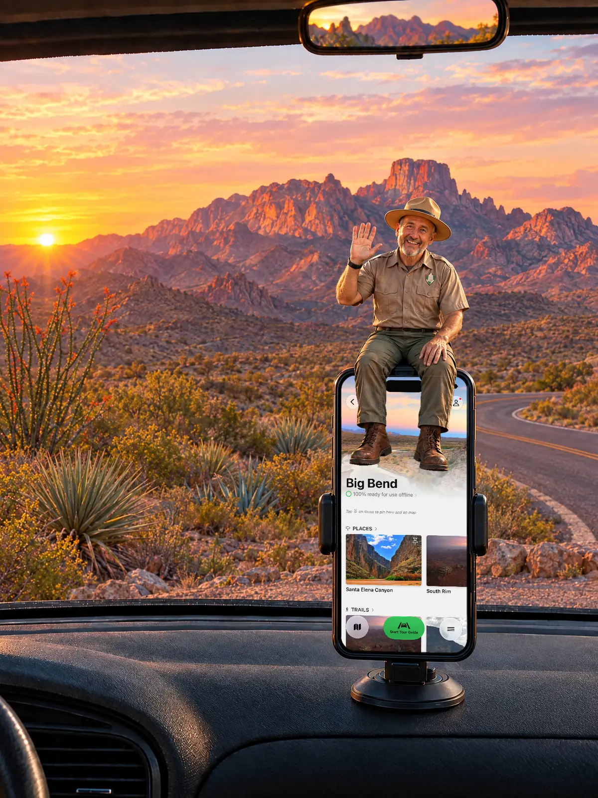 The Parkwolf tour guide waving from a dashboard phone at sunset, with the Chisos Mountains glowing ahead on the Ross Maxwell Scenic Drive