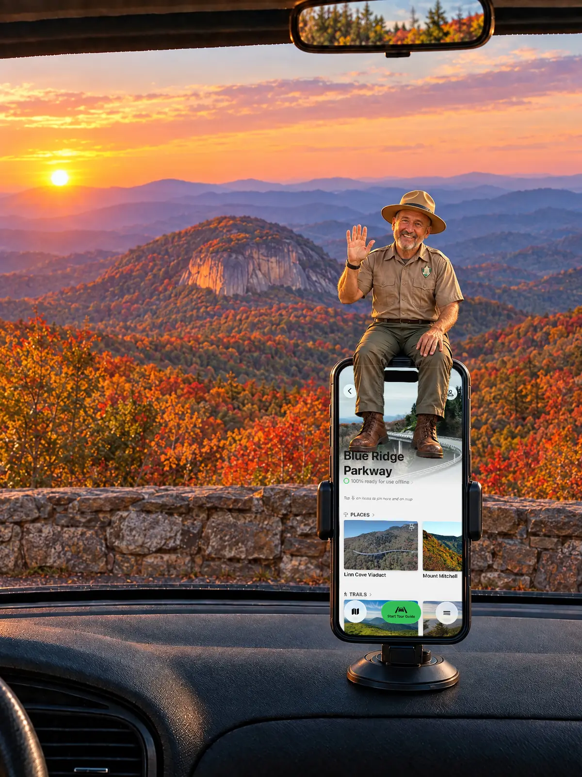 The Parkwolf tour guide waving from a dashboard phone at a stone-walled Blue Ridge Parkway overlook, facing Looking Glass Rock at sunset