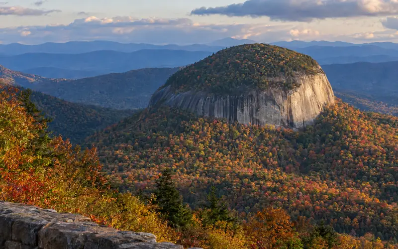 The bare granite dome of Looking Glass Rock rising above autumn forest, seen from a Blue Ridge Parkway overlook