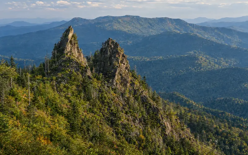 The jagged twin rock pinnacles of the Chimney Tops above a forested ridge, with Mount Le Conte behind