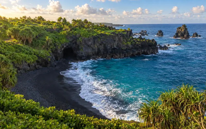 The black sand cove at Waiʻānapanapa State Park, ringed by lava cliffs and green naupaka